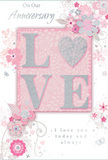 A softly romantic anniversary card fills the frame, its colour scheme of pastel pinks and silvery greys creating an atmosphere of cherished intimacy, reminiscent of a secluded table for two tucked off a Covent Garden side street. The central focus is the word LOVE, each letter gently raised and coated in pale, refined glitter, giving a subtle shimmer rather than a bold sparkle. The O has been transformed into a silver-textured heart, gleaming slightly more brightly than the rest, like a keepsake charm worn close to the skin. Around this centrepiece, delicate blooms in blush, mauve, and creamy white unfurl as if painted in watercolour, their edges softened and their lines flowing with the same easy grace a florist might use when arranging a loose, romantic bouquet for delivery around the Strand or Leicester Square. Fine tendrils, curling vines, and tiny petals weave between the larger flowers, while small butterflies and filigree flourishes add light movement, evoking the feel of an English garden just at the start of spring. The background is a gentle wash of pink, deepening behind the central design and fading outwards, creating a sense that the card is quietly glowing from within. Elegant, understated script-phrases such as On Our Anniversary and I love you today and always-appears in a soft, complementary tone, perhaps slightly glossy or raised to the touch. The overall effect is of a whisper-soft, profoundly heartfelt keepsake, perfectly suited to accompany fresh anniversary flowers sent from a local Covent Garden florist to mark a shared journey of love and memory in the heart of London.